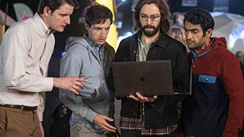 Four characters from a television drama crowded around a laptop.